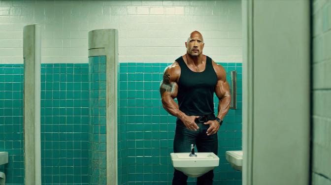 Dwayne The Rock Johnson standing at a bathroom urinal.